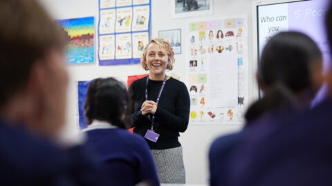 A-female-teacher-smiling-to-a-group-of-students-960x540.jpg