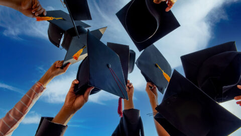 Graduates throwing graduation hats Up in the sky
